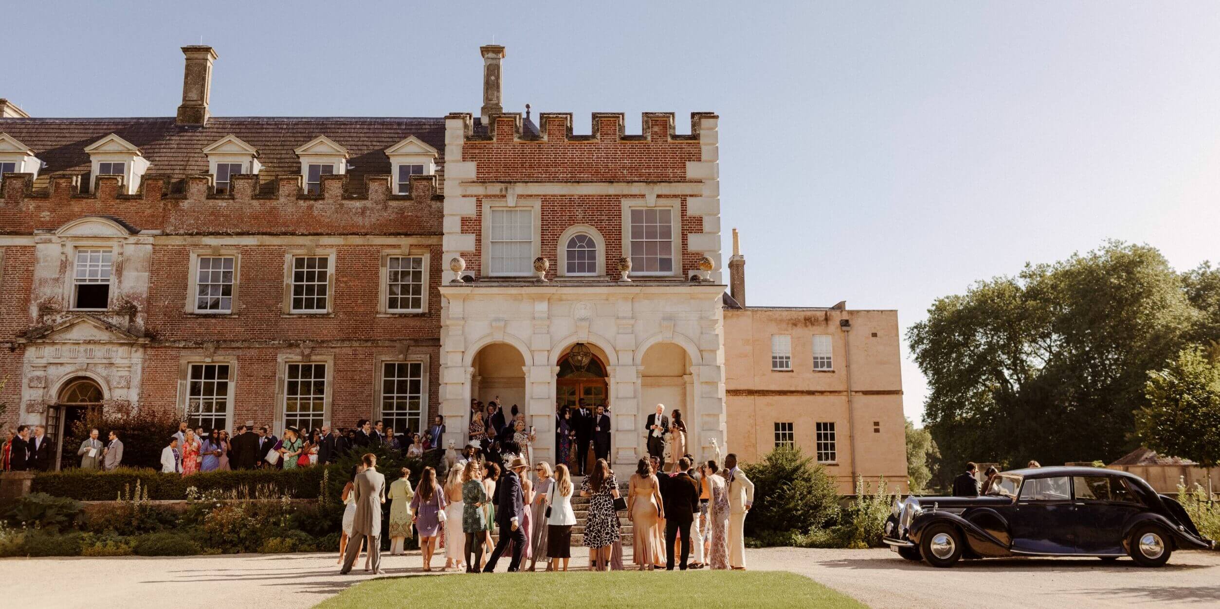 Weddings at St Giles House Guests gathering by the Daimler