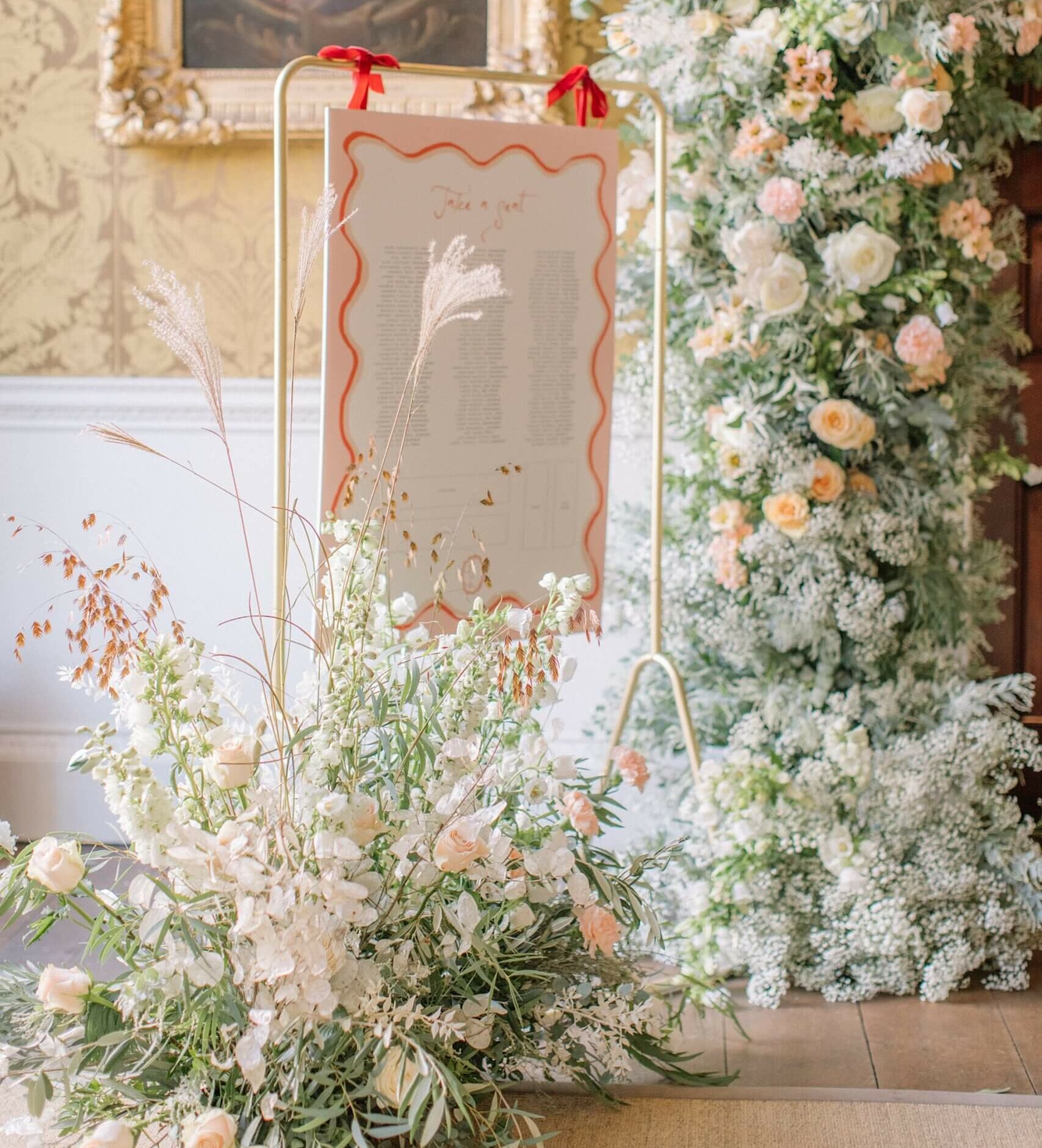 Pink and red florals surround a modern table plan for the wedding breakfast at St Giles House